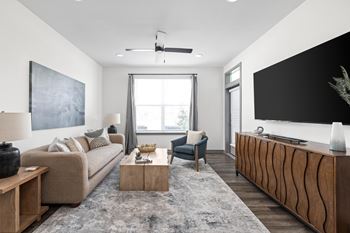 A modern living room with a large couch, a chair, a coffee table, and a flat-screen tv mounted on the wall.